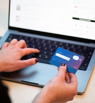 Persona pagando con tarjeta bancaria mientras usa un portátil, ilustrando la gestión de suscripciones online como ChatGPT Plus