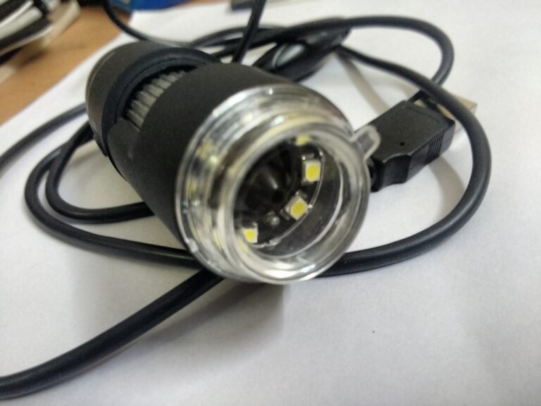 microscopio digital USB con cámara y luces LED sobre una mesa de trabajo