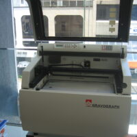 Grabadora laser de sobremesa con tapa abierta mostrando el cabezal y la mesa de trabajo