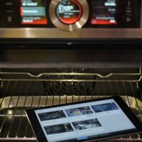 Interior de un horno eléctrico abierto con el panel de control encendido