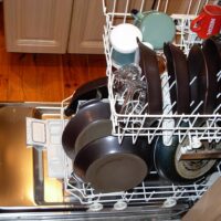Lavavajillas abierto y cargado con platos, vasos y sartenes