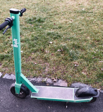 Patinete eléctrico plegado aparcado en la calle, visto de perfil