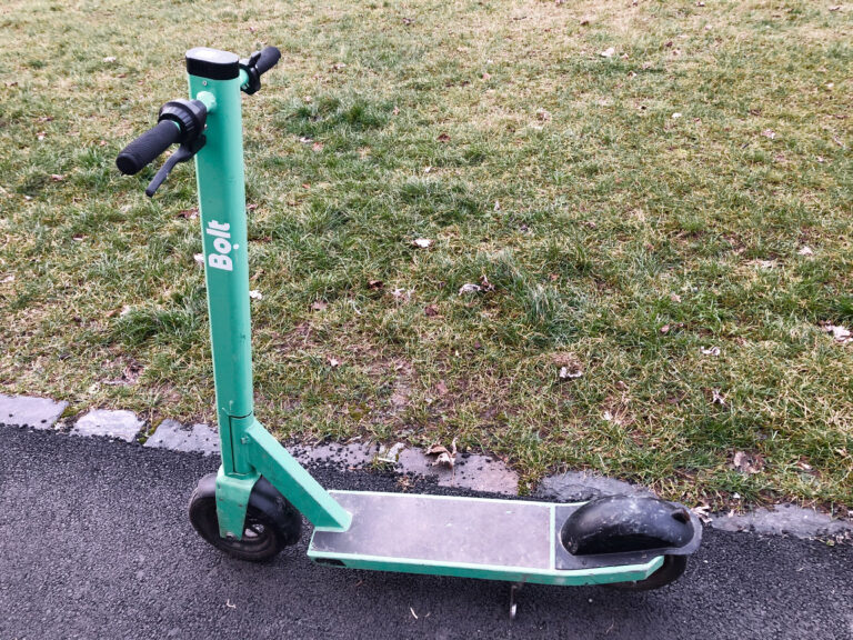 Patinete eléctrico plegado aparcado en la calle, visto de perfil