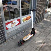 patinete eléctrico personal aparcado en una acera, con suspensión delantera y freno de disco a la vista