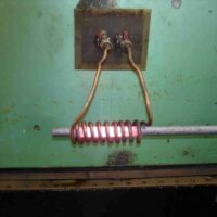 bobina de cobre de calentamiento por inducción poniendo al rojo vivo una barra de acero