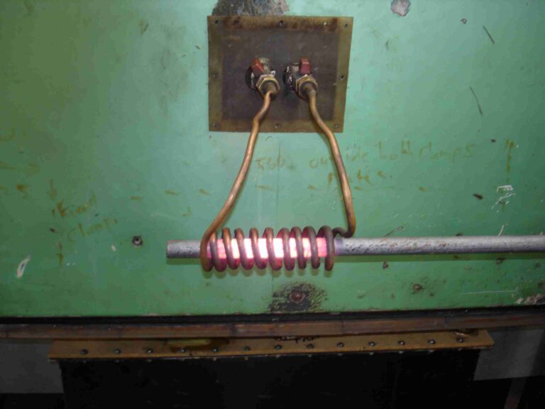 bobina de cobre de calentamiento por inducción poniendo al rojo vivo una barra de acero