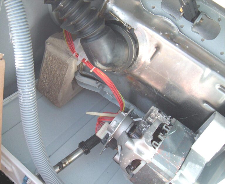 motor de una lavadora visto por dentro tras retirar la tapa trasera, con el cableado del sensor a la vista