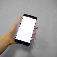 Mano sujetando un móvil con la pantalla táctil en blanco, sin responder