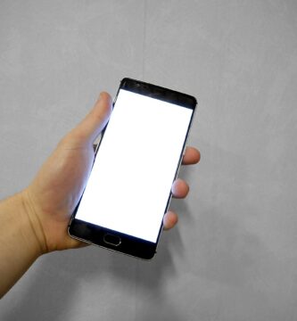 Mano sujetando un móvil con la pantalla táctil en blanco, sin responder
