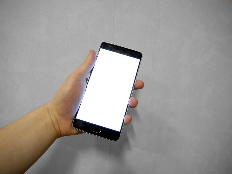 Mano sujetando un móvil con la pantalla táctil en blanco, sin responder